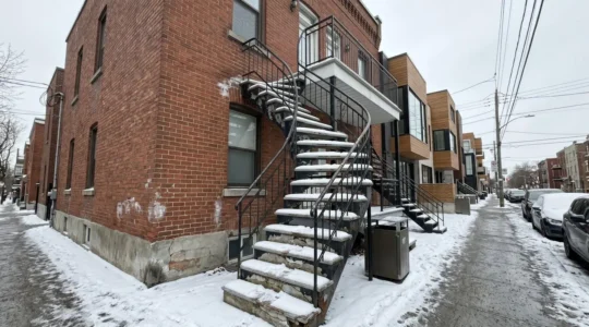 Escalier extérieur résidentiel avec marches en béton présentant des fissures visibles et un début d'effritement, accumulation de neige sur les côtés, architecture typique d'une maison montréalaise